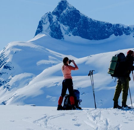 Tre personer på ski som ser utover et snødekket landskap