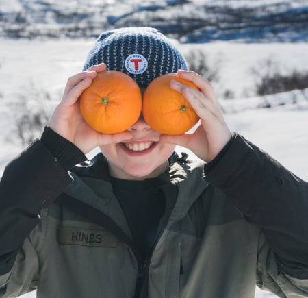 Gutt som holder to appelsiner foran ansiktet