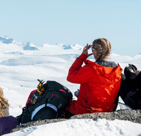 Tre personer som speider utover snødekte fjell