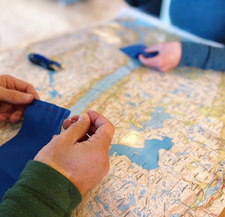 Noen hender som syr over et kart