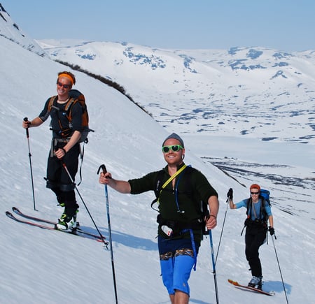 Gjeng på vei opp fjell med shorts og randoneeski.