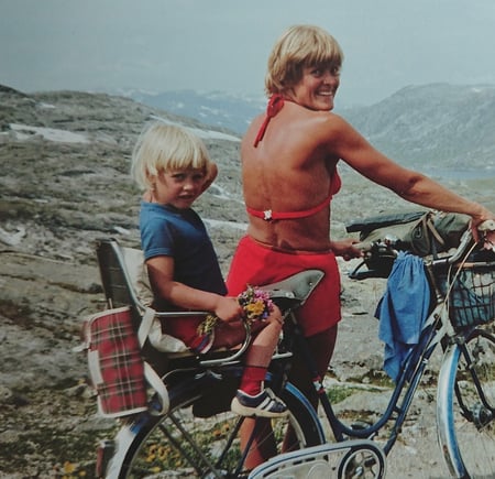 Finalebilder fra våren 2018. DNTs fotokonkurranse. Tema: Historiske bilder.
Mor og dotter på sykkeltur på Rallarvegen retning Hallingskeid sommaren 1981. Det var annan trend då med tregirs sykkel og ingen hjelm på verken vaksene eller born. Innsendar av biletet er meg, Heidi Reisegg Endal, som sit bak på sykkelen. Det er min far Richard Jacobsen som har teke biletet. Sykkelen fekk mor mi (Tove Reisegg Jacobsen) i konfirmasjonsgåve i 1962. På den tida var det eksklusivt å ha sykkel med tre gir.
Mine foreldre har samtykka til at eg kan sende inn biletet.