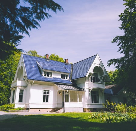 bilde av et hvitt hus med grønne trær rundt.