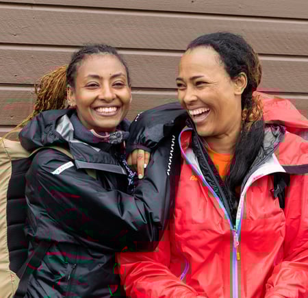 To kvinner står sammen med turklær på og smiler