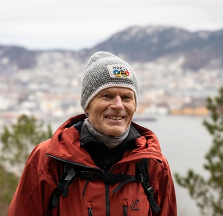 Mann med lue smiler på fjell.