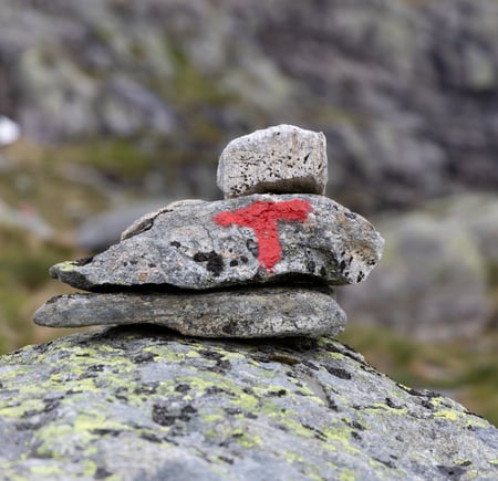 Rødmalt T på varde med tre steiner.