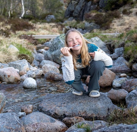 jente pusser tennene i bekk og smiler