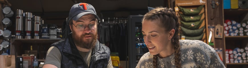 En DNT ansatt som veileder en kunde i turruter og kart.