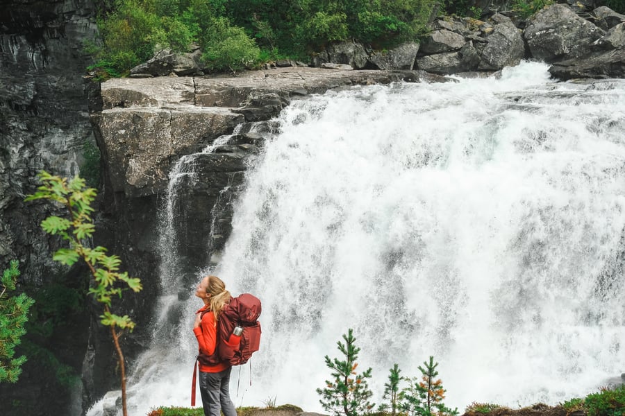 jente står foran en stor foss og nyter naturens lyder