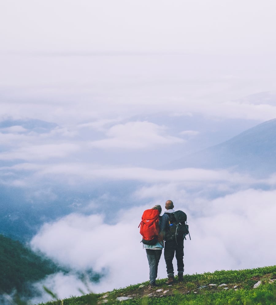 To turgåere ser utover tåkehav fra fjelltopp
