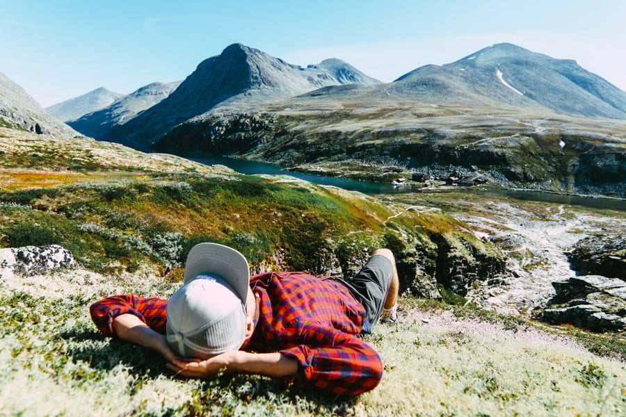 Person som ligger på mose i fjellandskap