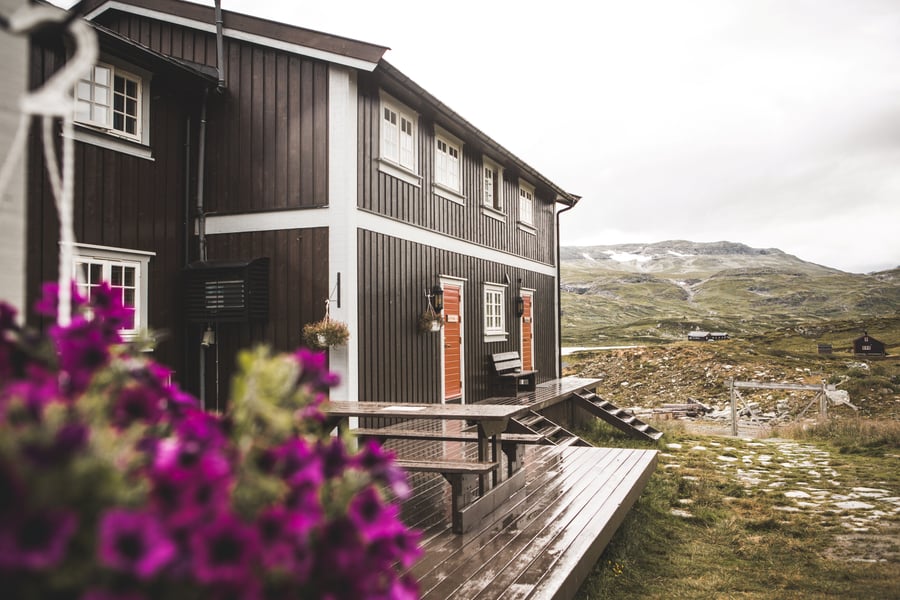 Brun hytte med fine blomster foran.