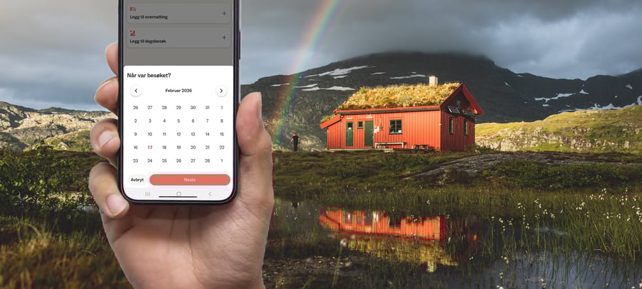 Mobiltelefon med DNT-app foran hytte i fjellet