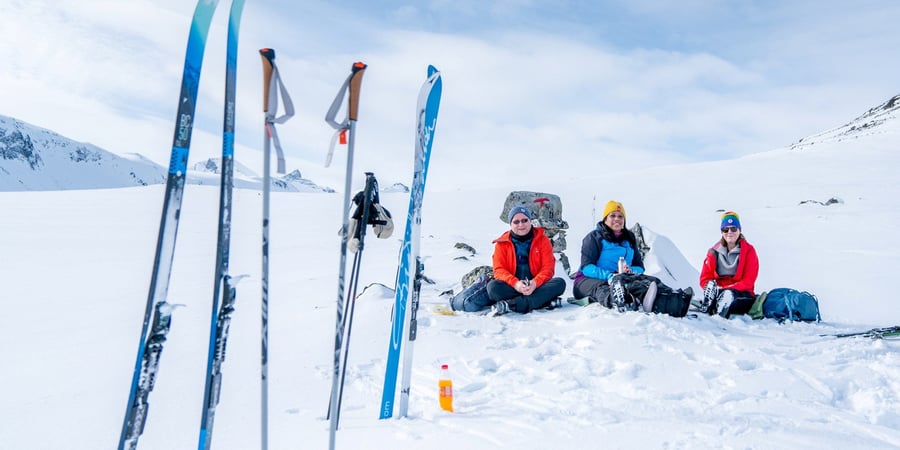 Tre personer som sitter og soler seg i vinterfjellet