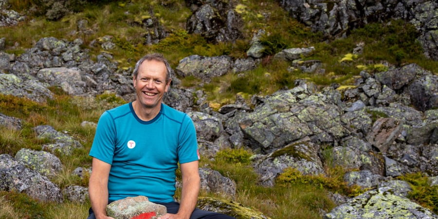 En mann sitter med en stein mellom beina som er merket med en rød T.