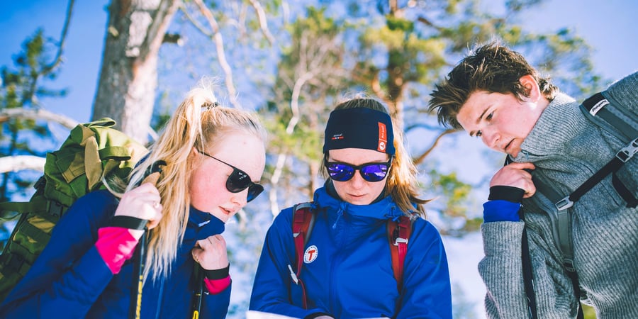 Tre unge mennesker studerer kart