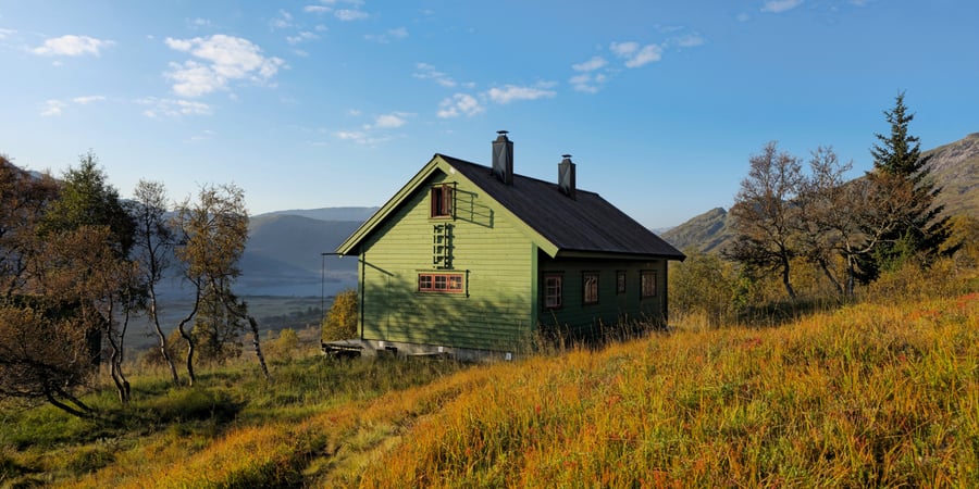 Grønn hytte i dal med høstfarger.