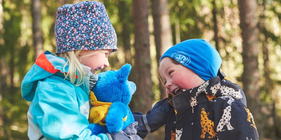 To barn i uteklær som smiler og ler