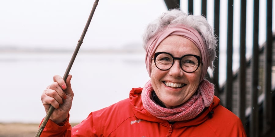 En kvinne med rød jakke smiler til kamera.