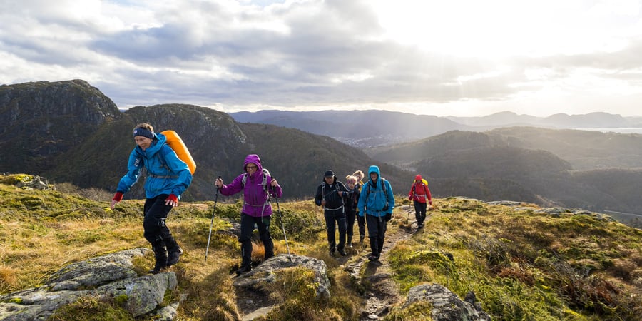 En gruppe seniorer går på sti oppover et fjell