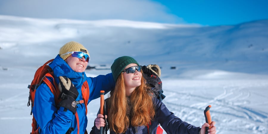 To kvinner på skitur med sekk på ryggen. Fjell.