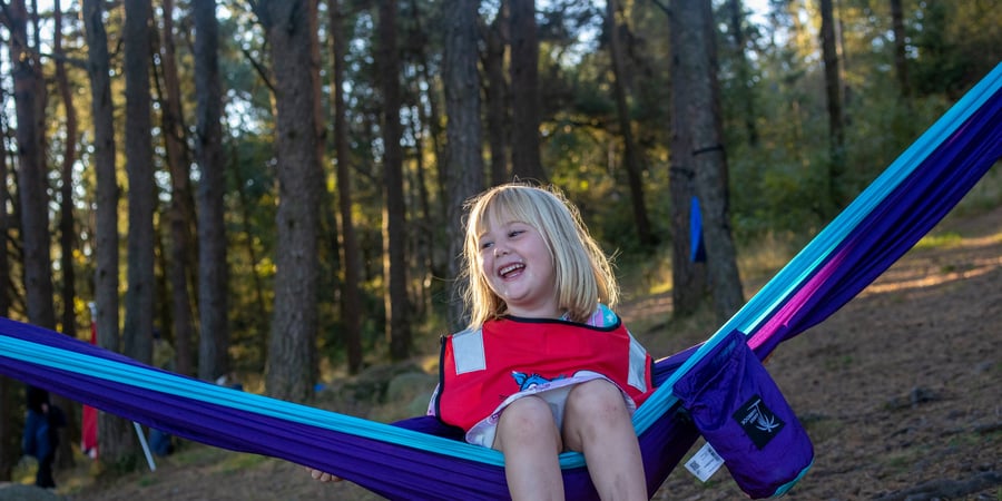 Et barn sitter i en hengekøye