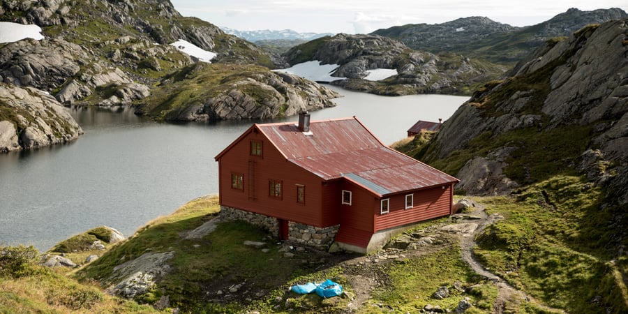 Slitt, rød hytte i fjellet.