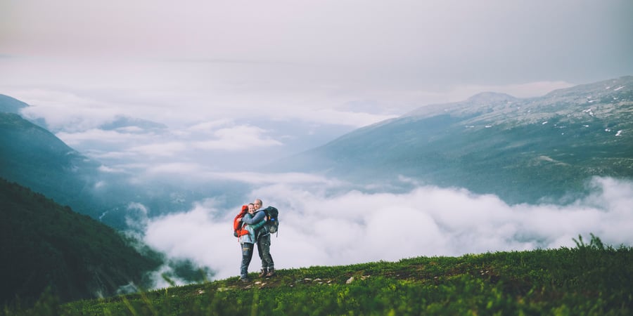 to mennesker klemmer hverandre på fjelltur