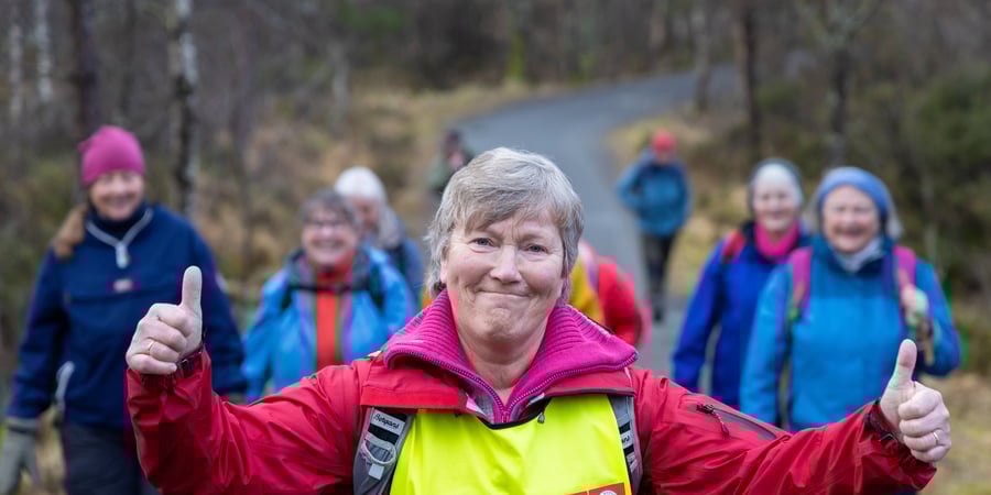 En gruppe med turgåere sitter på et berg og spiser matpakkene sine med utsikt over Byfjellene.