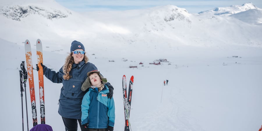 Fire kvinner sitter i vinterlandskap og smiler. Hun ene kaster en appelsin mot hun andre.