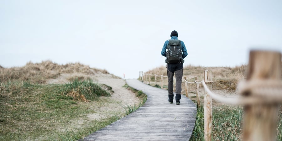 En mann går utover en sti laget av trelemmer.