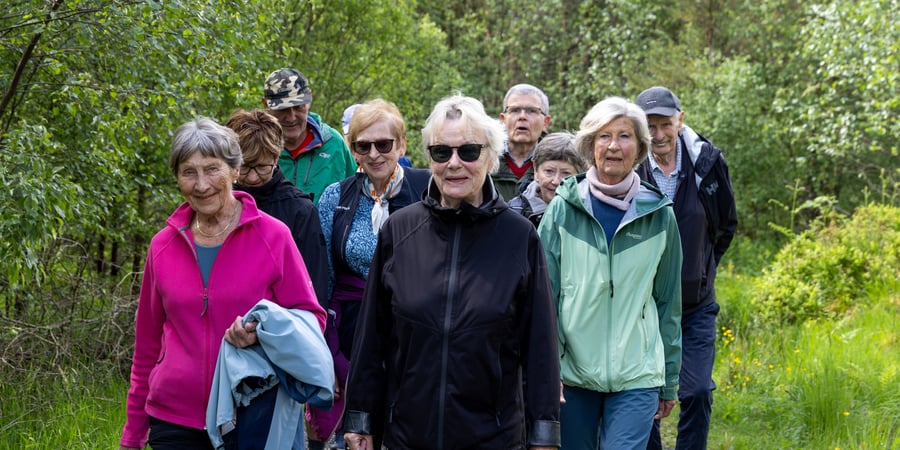 En gruppe med turgåere sitter på et berg og spiser matpakkene sine med utsikt over Byfjellene.