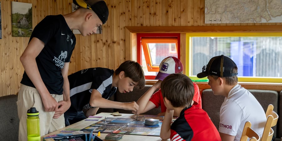 En gjeng med gutter sitter rundt et bord og spiller spill. 
