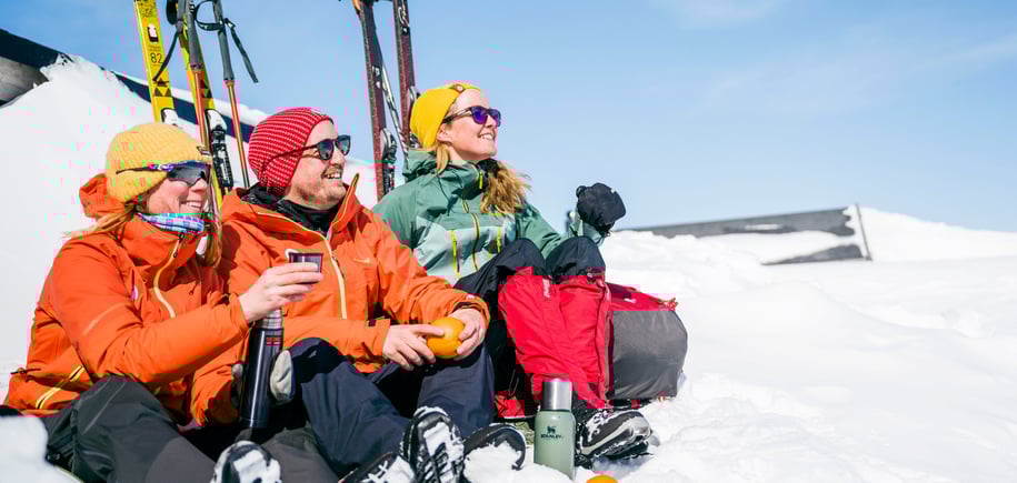 tre påsketurister i solveggen, koser seg med kaffe og appelsin
