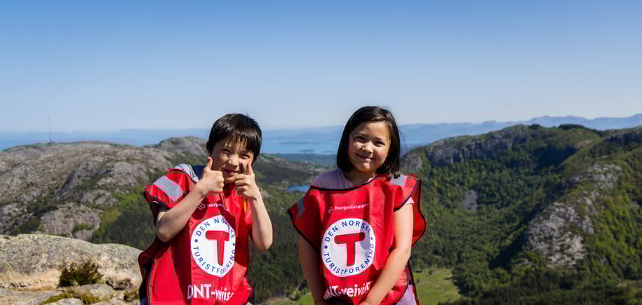 To barn med røde T-vester smiler til kamera.