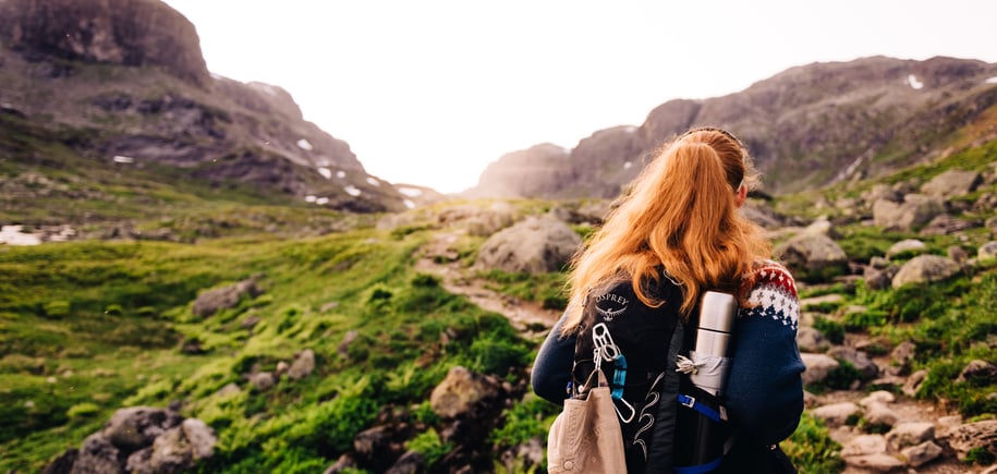 Foto. Turgåer med sekk. Fjell og grønt gress.