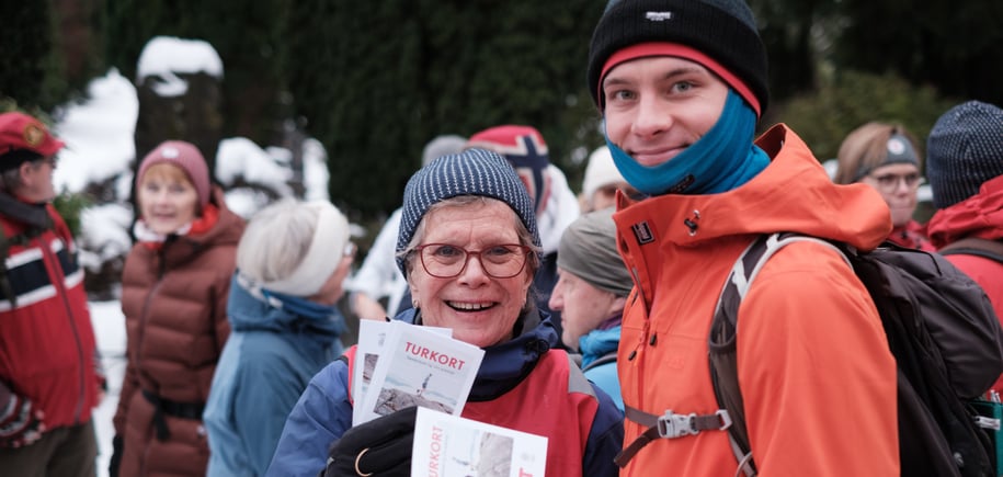Kvinne og mann står med turklær på og viser frem et kort. 