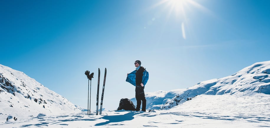Mann tar av jakke i vinterfjellet