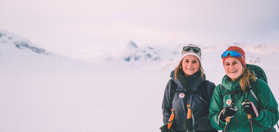 To smilende damer på ski på vinterfjellet. 
