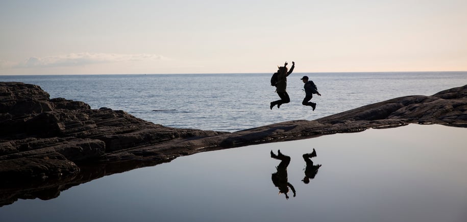 To personer hopper i solnedgang ute i havgapet. Foto 
