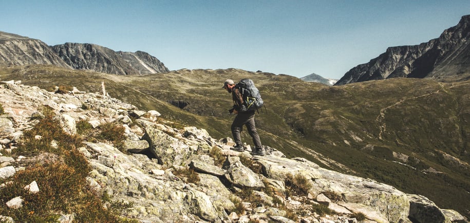 Mann med sekk som går i fjellet