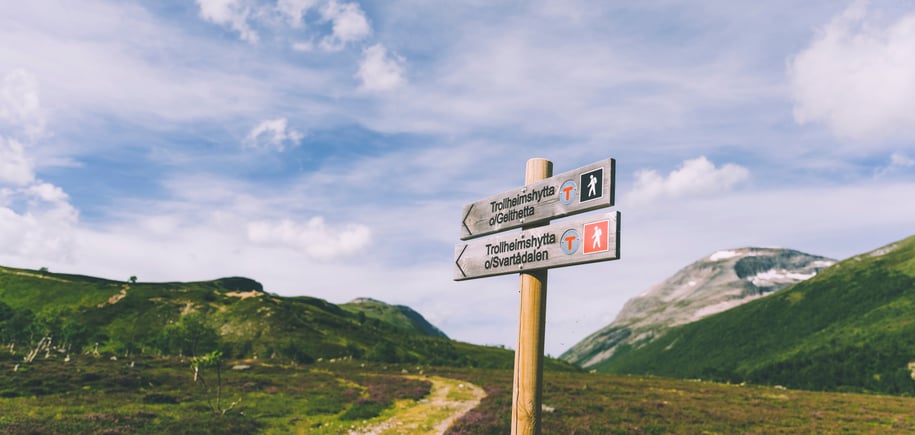 Skilt som viser mot en sti innover fjellet