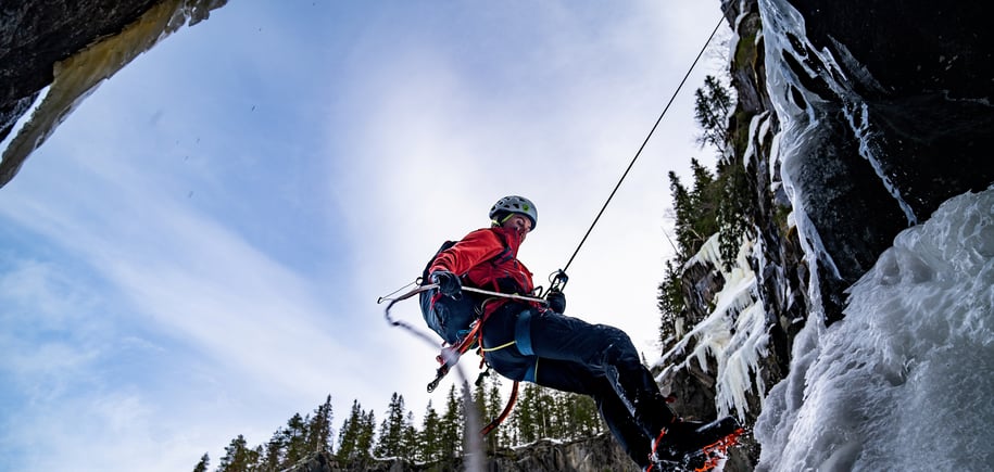 Isklatrer henger i tau ved frosset foss.