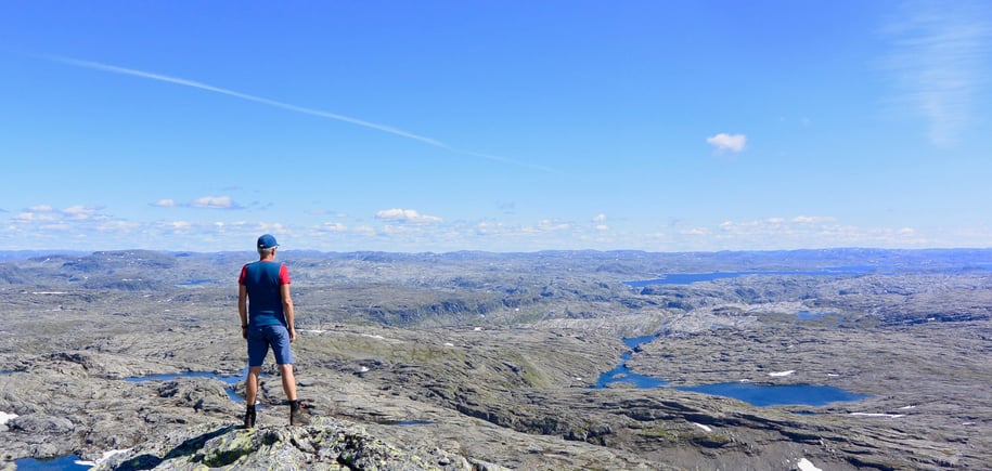 En mann som speider utover et fjelllandskap.