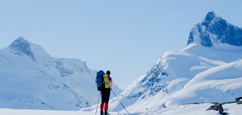 Dame som står på ski og ser på et fjell