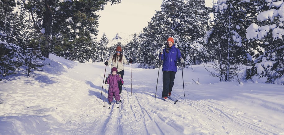 To voksne og et barn som går på langrenn