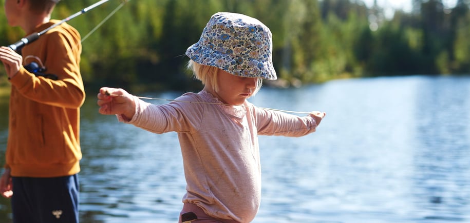 Barn med solhatt som balanserer på en stokk