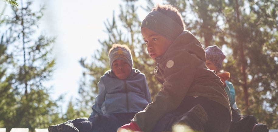 Flere barn som sitter på bakken i skogen