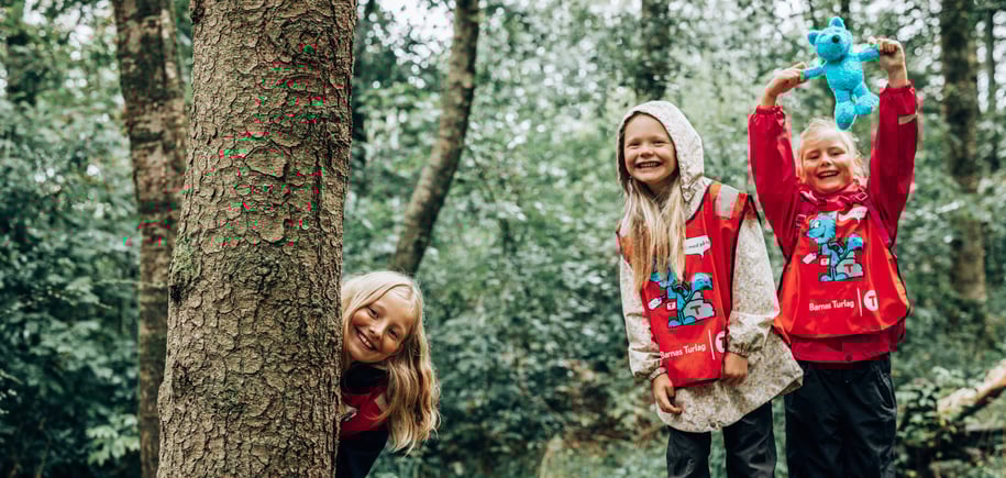 Tre jenter leker i skogen med blå Turbo-bamse