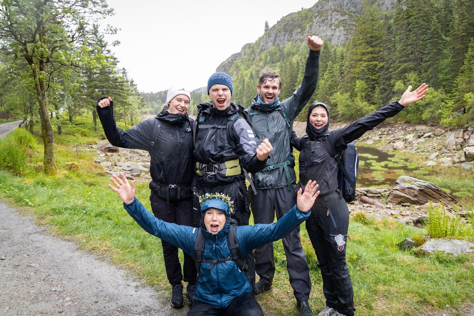 Gruppe mennesker strekker hendene i været og jubler 